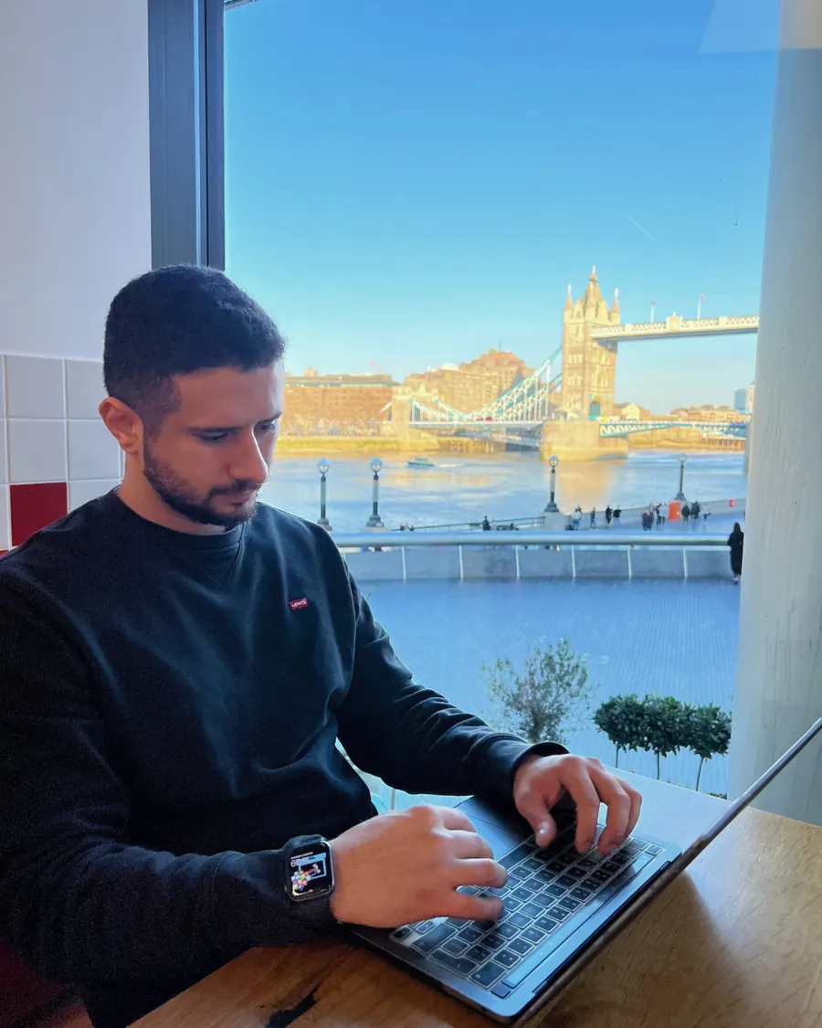 Lucas working on a laptop next to a window overlooking Tower Bridge in London