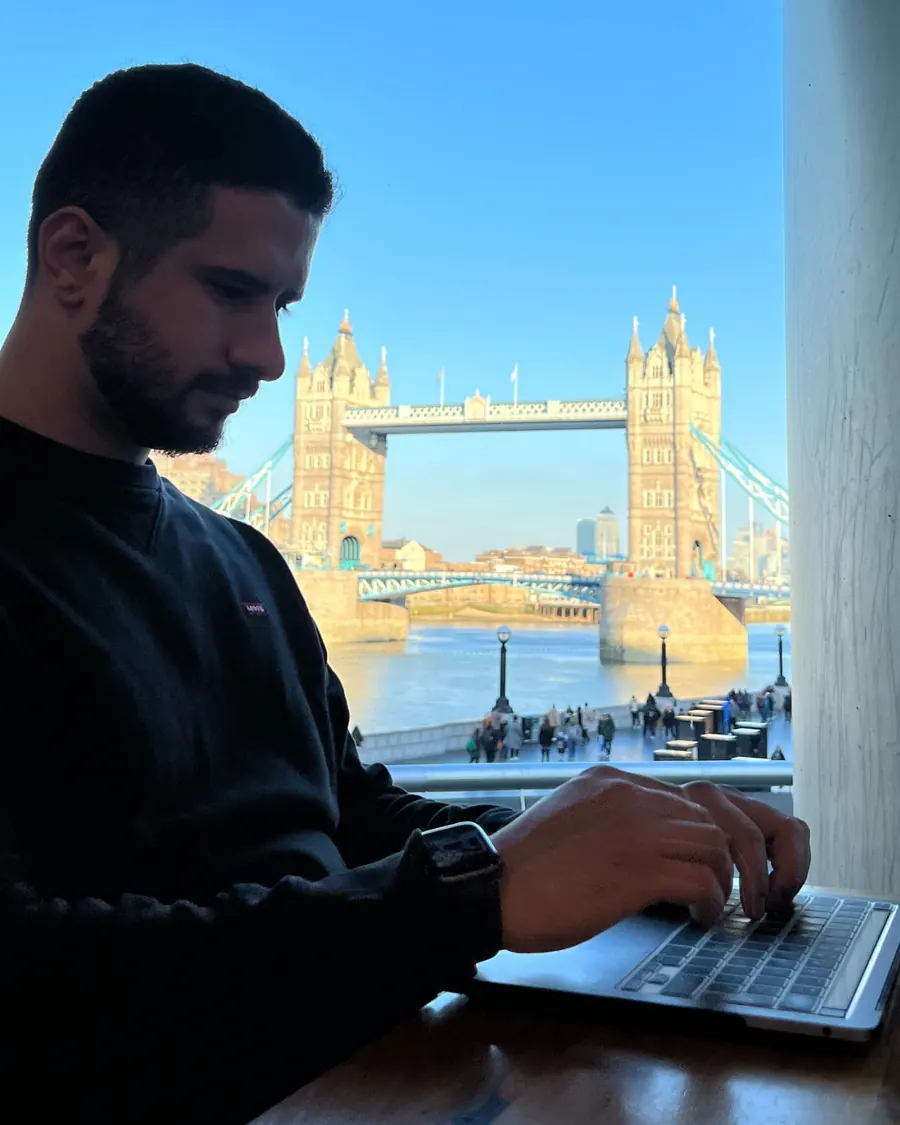 Lucas in profile working on a laptop in front of Tower Bridge